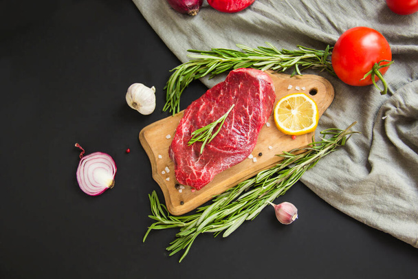 Raw beef steak on a cutting board with spices. Creative atmospheric decoration. - Photo, Image