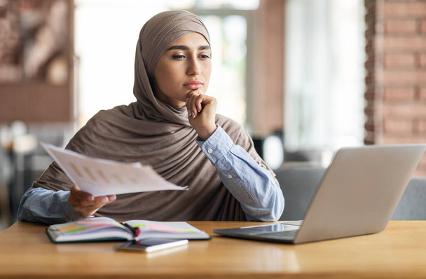 Pensive muslim woman manager working while sitting at cafe - Photo, image