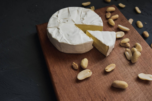 τυρί καμαμπέρ με μούχλα και ξηρούς καρπούς σε ξύλινη σανίδα - Φωτογραφία, εικόνα