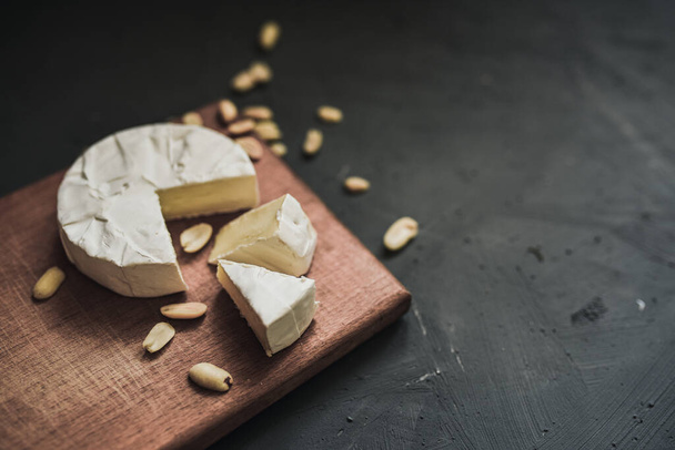 cheese camembert with mold and nuts on wooden board - 写真・画像