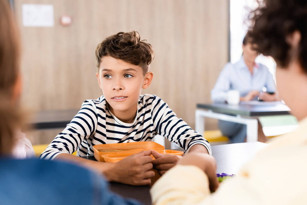 同級生の近くの学校の食堂に座っている少年の選択的な焦点 - 写真・画像