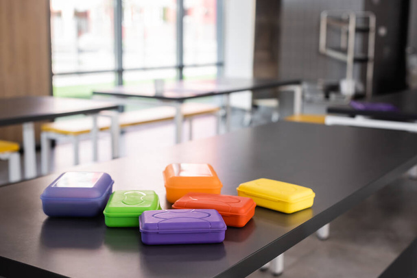 coloridas cajas de almuerzo de plástico en la mesa en el comedor de la escuela - Foto, imagen