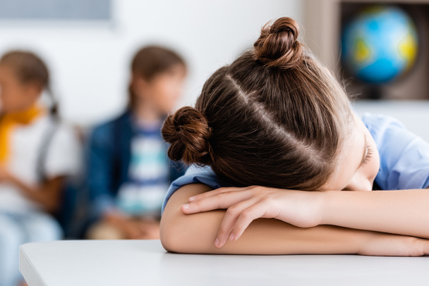 Valikoiva painopiste koulutyttö nukkuu pöydällä luokkahuoneessa  - Valokuva, kuva