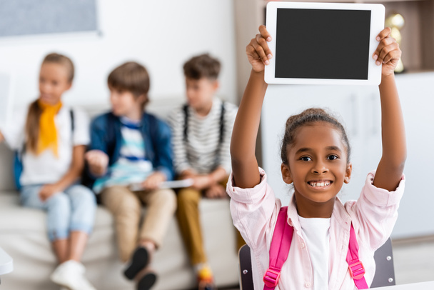 Selektivní zaměření africké americké školačky držící digitální tablet s prázdnou obrazovkou ve třídě  - Fotografie, Obrázek