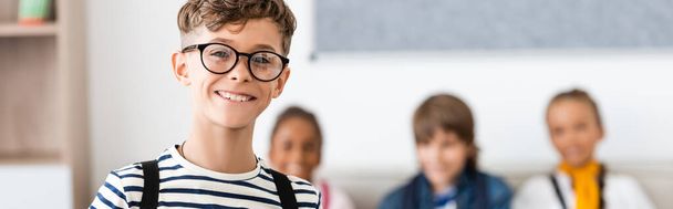 Horizontal concept of schoolboy looking at camera with multiethnic classmates at background  - Photo, image