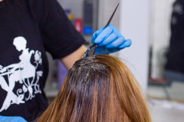 kapper op het werk, jonge kapper verft het haar van de klant - Foto, afbeelding