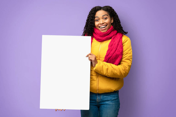 陽気なアフリカ系アメリカ人の女の子は、ブランク冬のポスターを保持、スタジオショット - 写真・画像