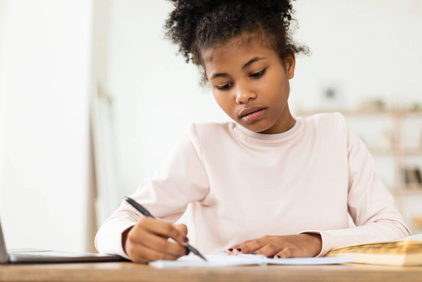 czarny nastolatek dziewczyna pisanie robi praca domowa nauka siedzi w domu - Zdjęcie, obraz