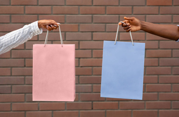 Shopper, Einkaufszentrum und Einkauf. Hände von afrikanisch-amerikanischem Kerl und Mädchen halten rosa und blaue Pakete - Foto, Bild