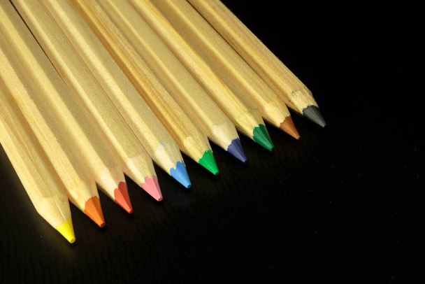 Деревянные красочные обычные карандаши изолированы на темном фоне. Образовательное оборудование - Фото, изображение