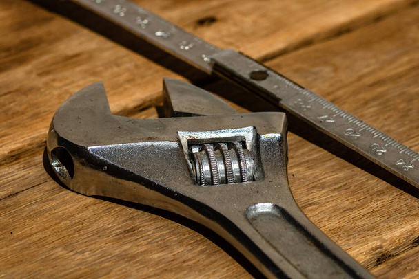 Gereedschap voor reparatie en bouw. Hummer, instelbare sleutel, liniaal. Instrumenten op rustieke houten tafel met kopieerruimte - Foto, afbeelding