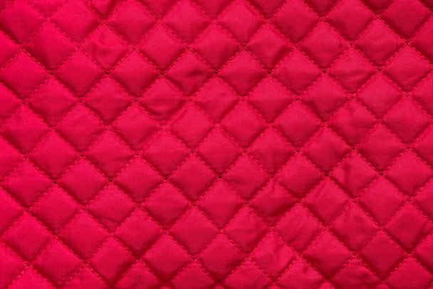 rood gestikt gewatteerde zak doek achtergrond closeup - Foto, afbeelding