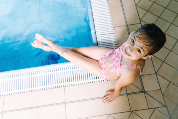 Portrait girl having fun in indoor swimming-pool. The girl is resting at the water park. Active happy kid. Swimming school for small children. Concept friendly family sport and summer vacation - Фото, зображення