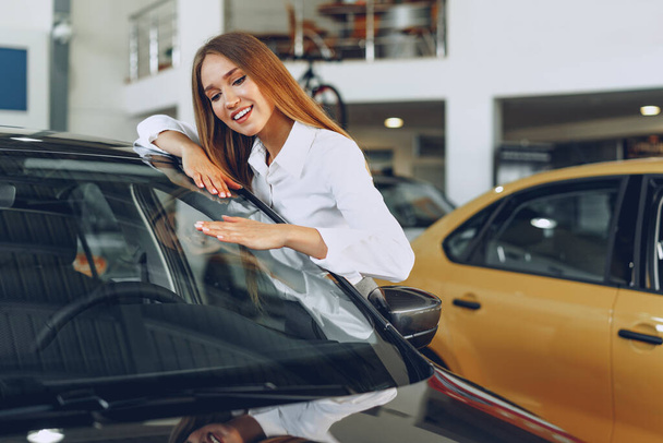 Beautiful young woman touching her new car with pleasure - Фото, изображение