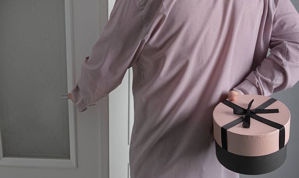 man opens the door and holds a gift in round box.Present concept - Photo, Image