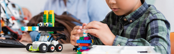 Panoramic crop of schoolboy with building blocks modeling robot in stem school - Photo, Image