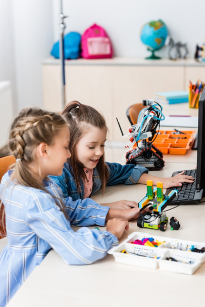 Az iskolás lányok szelektív fókusza a robot modellezésére az ősiskola építőelemeiből  - Fotó, kép
