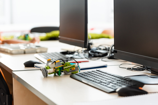 Селективный фокус робота на столе рядом с компьютерами в начальной школе  - Фото, изображение