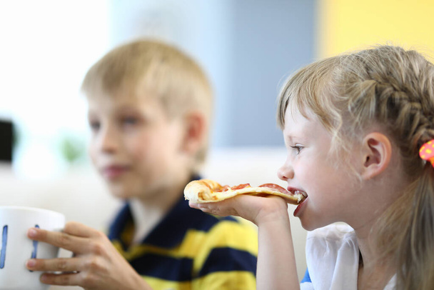 Kleines Mädchen beißt Pizzabote mit Tasse. - Foto, Bild