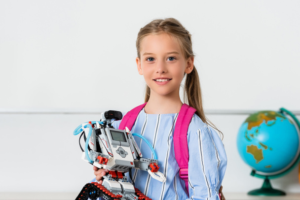 Robot tutan ve sınıftaki kameraya bakan kız öğrenci.  - Fotoğraf, Görsel