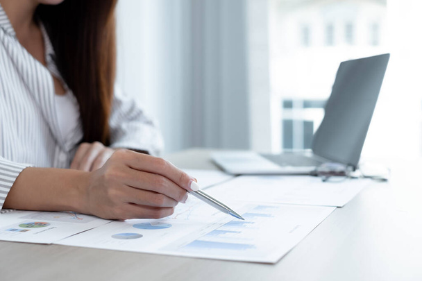 Asian female accountant sits at their desks and calculates financial graphs showing results about their investments, plan a successful business growth process. - Photo, Image