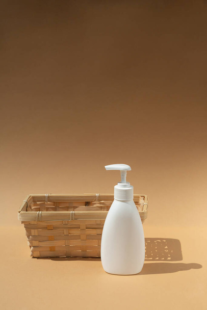 cesto di vimini e bottiglia bianca dispenser, per prodotti cosmetici spa su sfondo beige. - Foto, immagini