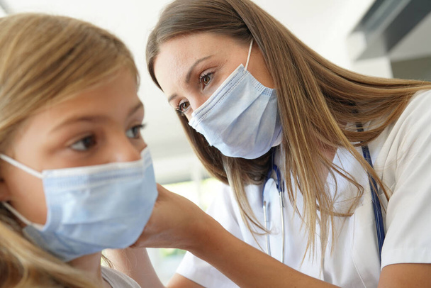 Kid at doctor's office with protection face mask having temperature checked - Photo, Image