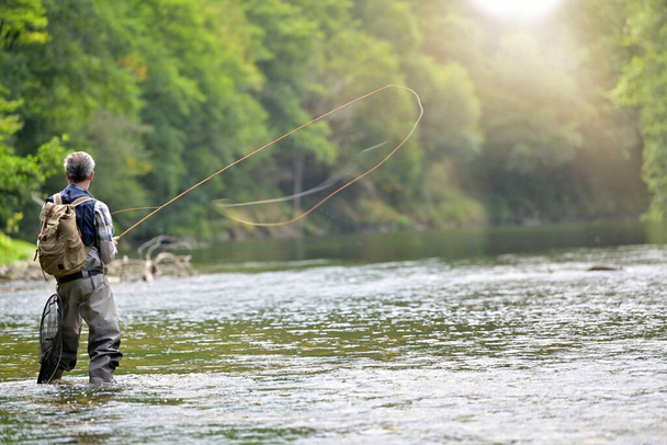 Man fly fishing in the summer in a beautiful river with clear water - Foto, Imagen