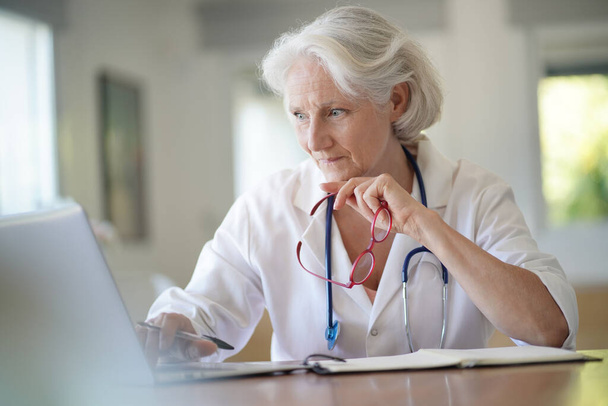 Senior woman doctor working on laptop - Foto, Imagen