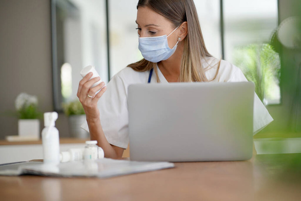 Portrait of nurse working in office and wearing face mask  - Фото, зображення