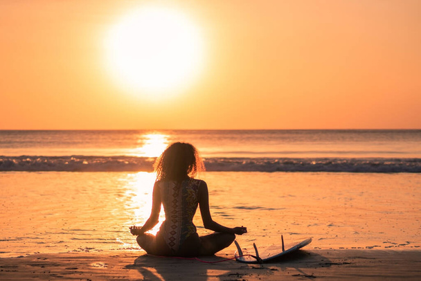 Portrait of woman surfer with beautiful body on the beach with surfboard at colorful sunset in Bali - Foto, imagen