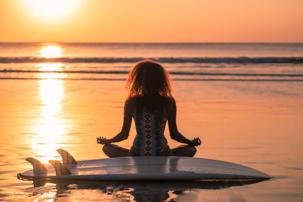 Portrait of woman surfer with beautiful body on the beach with surfboard at colorful sunset in Bali - Fotoğraf, Görsel