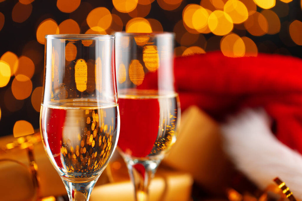 Champagne and Santa Claus hat on blurred garland background - Photo, image