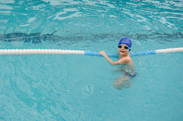 top view of a 7-year boy playing and swimming in the swimming pool - Foto, Imagem