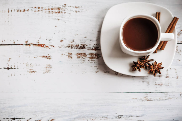 una tazza di caffè con bastoncini di cannella su uno sfondo di legno chiaro. spazio per il testo - Foto, immagini