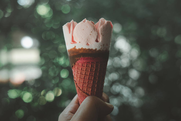 Ice cream strawberry wafer in hand against on nature blur background. Close up - Foto, Bild