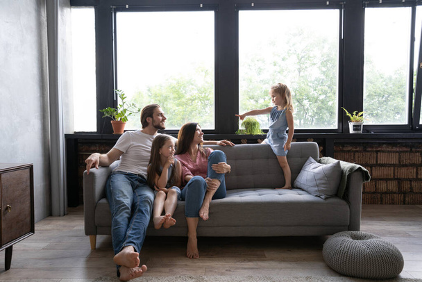 Cheerful family at home sitting in sofa. - Fotó, kép
