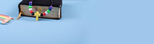 пластикове намисто хреста та чорна Біблія на синьому фоні з копіювальним простором. Церква, школа Біблії, християнська концепція. Вибраний фокус
.  - Фото, зображення