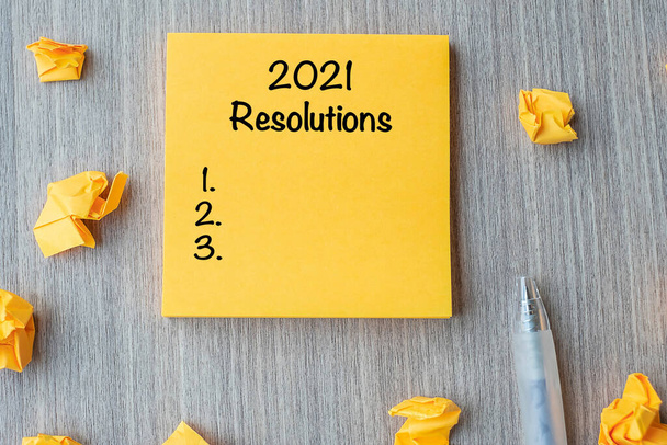 2021 RESOLUTIONS слово на жовтій ноті з ручкою і подрібненим папером на дерев'яному тлі столу. Новий старт, Стратегія та концепція цілі
 - Фото, зображення