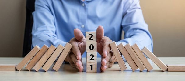 ビジネスマンの手2021木製ブロックの落下を停止します。ビジネス、リスク管理、保険、解決、戦略、ソリューション、目標、新年のあなたと幸せな休日の概念 - 写真・画像