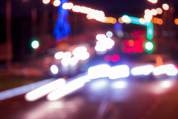 Ślady reflektorów z samochodów poruszających się nocą po moście, oświetlone latarniami. Abstrakcyjny rozmazany krajobraz miasta z autostradą o zmierzchu.  - Zdjęcie, obraz