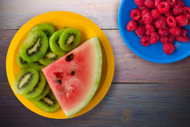 watermelon and kiwi sliced on a yellow plate or a purple wooden background.vegan food top view - Фото, зображення
