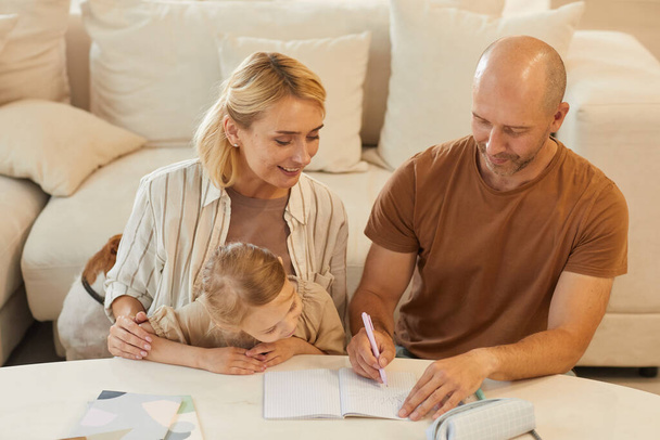 Портрет щасливої сім'ї матері та батька, який допомагає милій маленькій дівчинці малювати на навчання вдома, копіювати простір
 - Фото, зображення