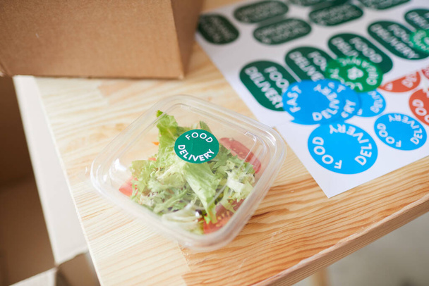 Taze salata porsiyonunu, sağlıklı yemek dağıtım servisindeki ahşap masadaki plastik ambalajla kapatın. - Fotoğraf, Görsel