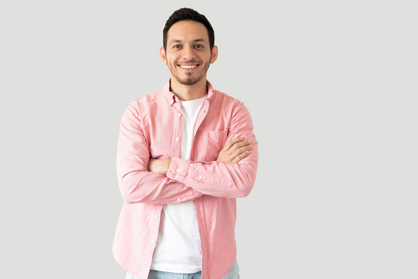 Retrato de un hombre hispano guapo con ropa casual sonriendo en un estudio - Foto, imagen