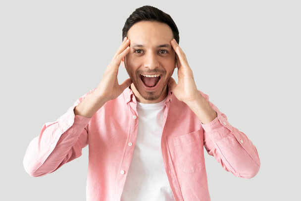 Good looking young man looking surprised and screaming with excitement in a studio - Foto, imagen