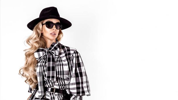 Checkered fashion. High fashion portrait of young elegant woman in checkered outfit. Black and white tartan clothing, sunglasses and hat isolated on white background. - Fotoğraf, Görsel