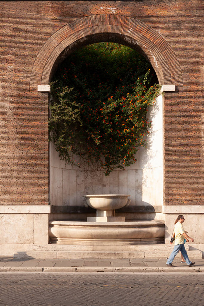 Roma, Italia - 27 de junio de 2010: Una pareja de turistas pasa frente a la Fuente de los Foros Imperiales, Roma. - Foto, Imagen