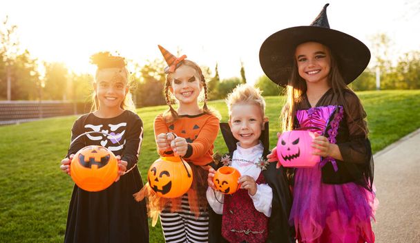 Optimistic kids in creepy costumes smiling for camera  while trick or treating in par - Φωτογραφία, εικόνα