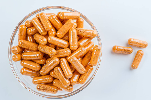 Brown pills in a glass bowl on a light background. - Photo, image
